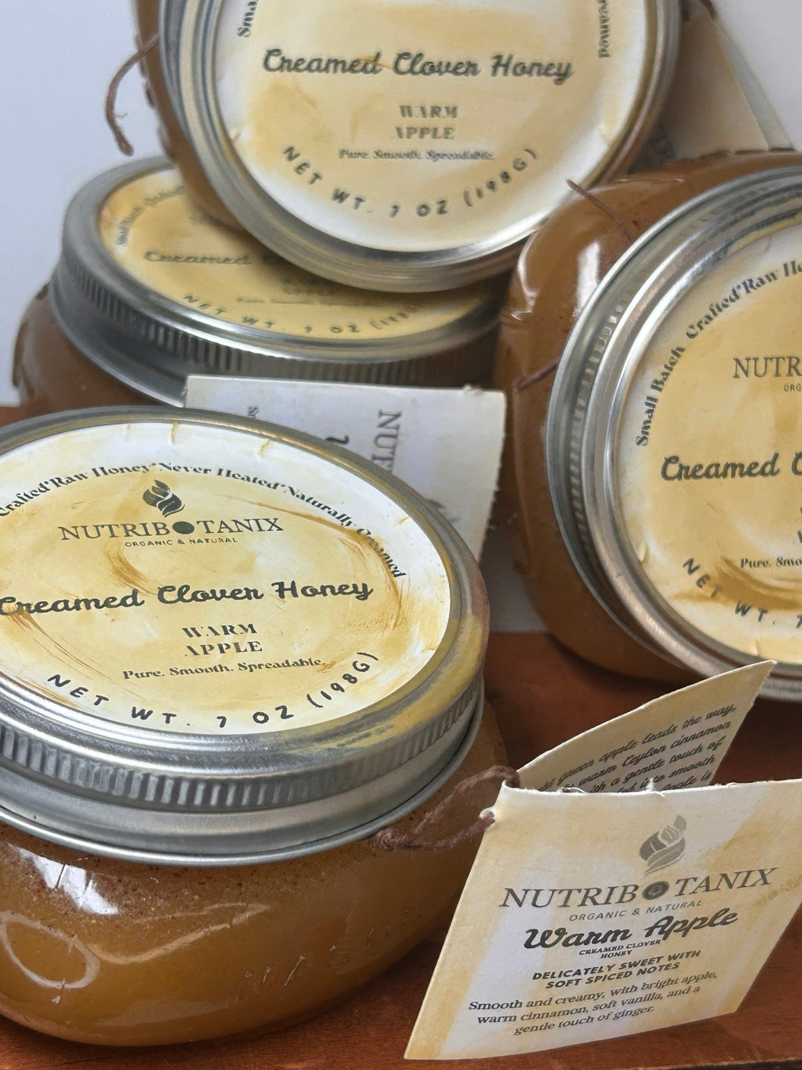 NutriBotanix Warm Apple Creamed Clover Honey in 7 oz glass jars with yellow labels.